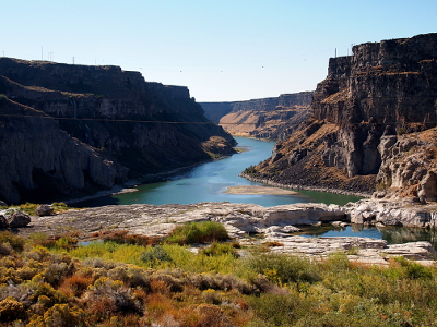 [The falls are not visible. One views rock and vegetation in the foreground leading to water snaking through the high canyon walls in the mid and background.]